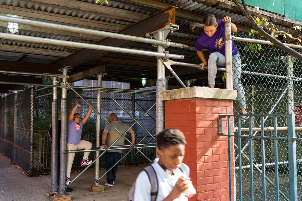 Children climb on the scaffolding outside of their school building