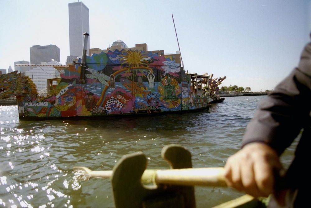 A colorfully painted boat floats near the Manhattan skyline