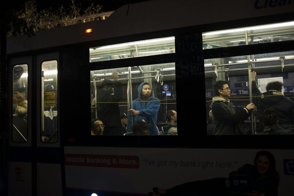Passengers stand and sit inside a subway car at night