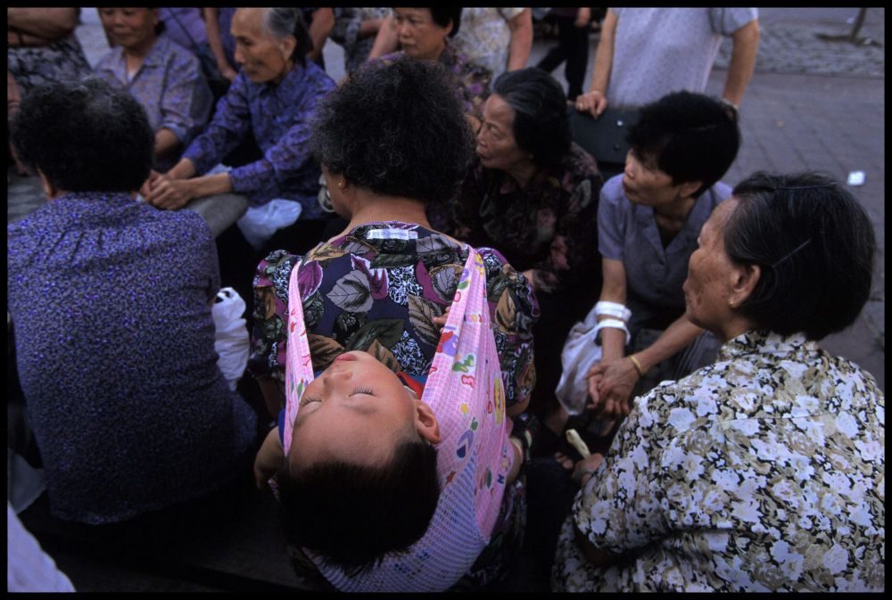A baby sleeps in a carrier strapped to a woman’s back