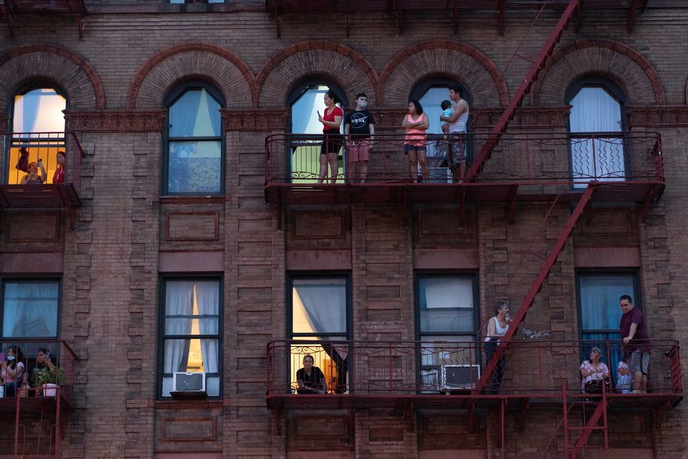 Residents of a Bronx apartment building look out at the street from their fire escapes