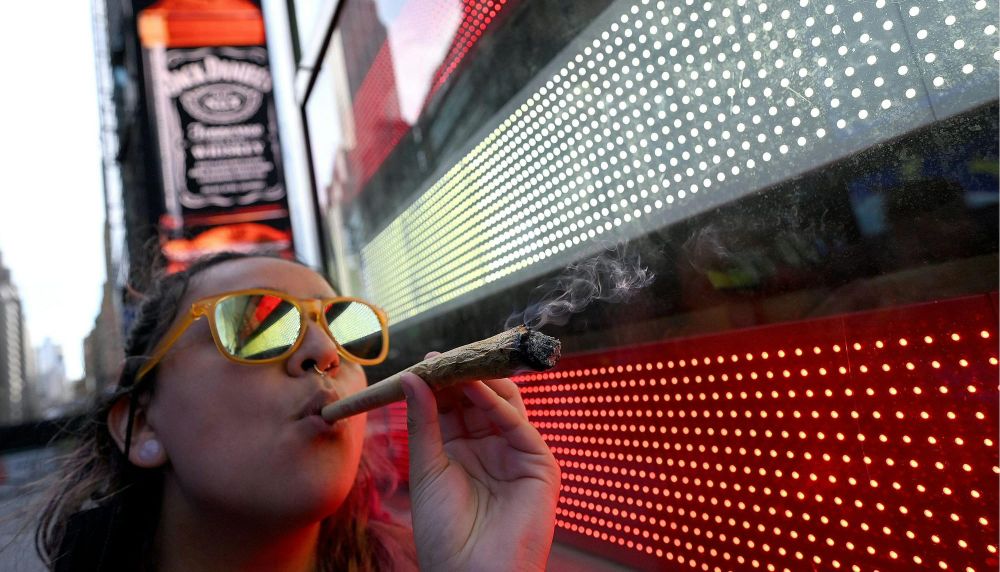 A woman smokes a large marijuana cigarette in Times Square