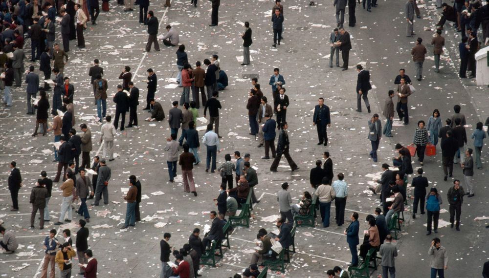 An aerial view of a crowded plaza littered with paper