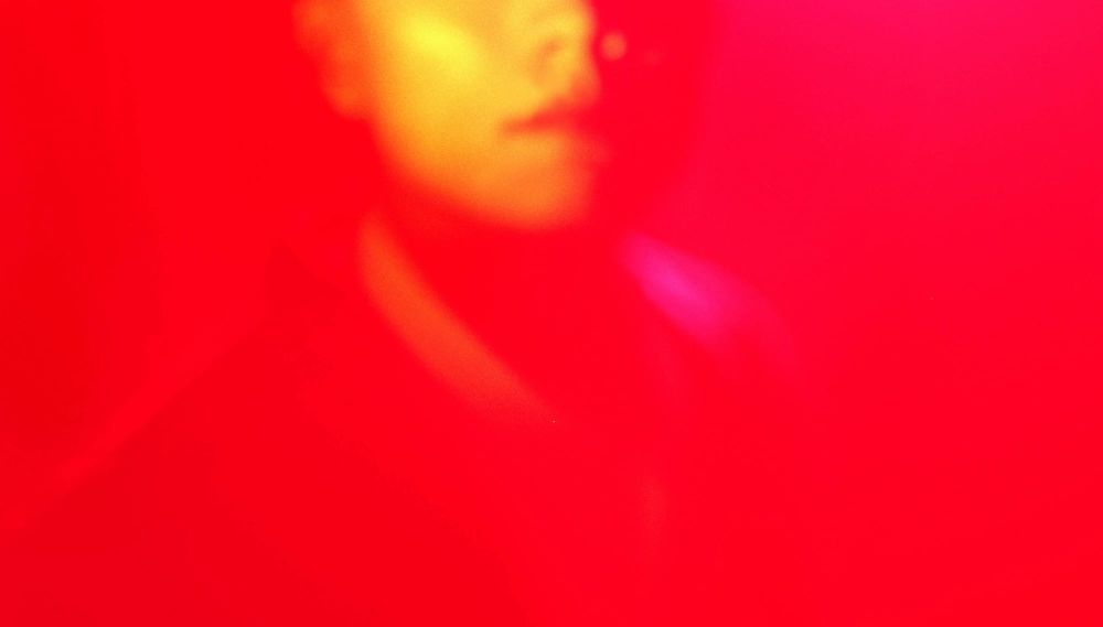 A face obscured by bright pink light