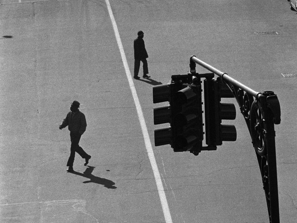 Two men cross a street, seen from above near a traffic light