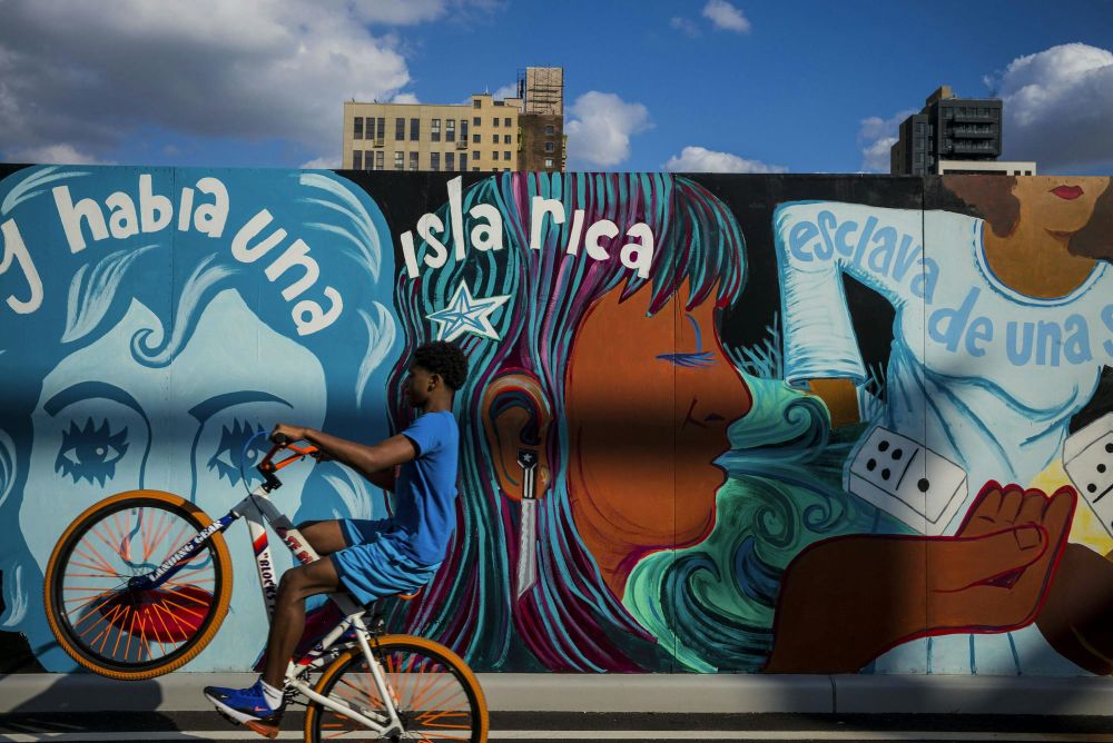 A child doing a wheelie trick on his bike in front of a colorful mural