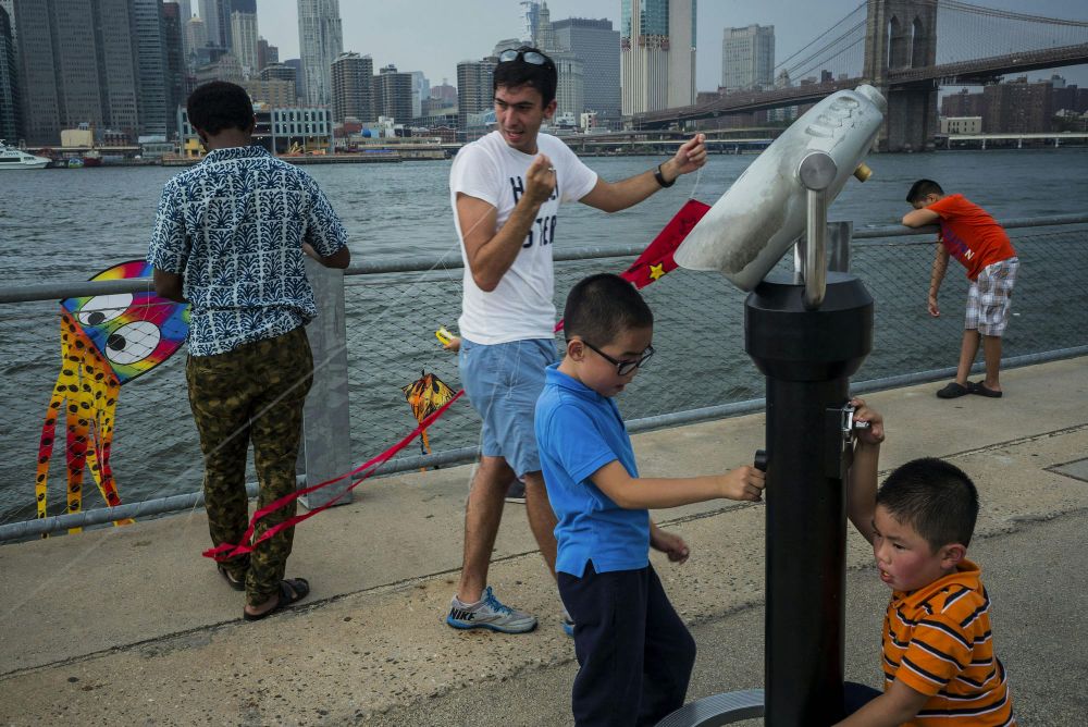 A group of parents and children gathered by the waterfront at Brooklyn Bridge Park to celebrate a kite festival