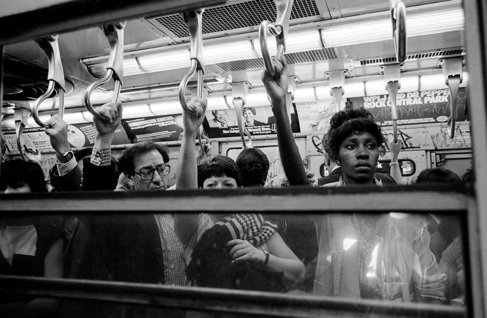 Passengers stand hanging onto the straps in a 1980 subway car
