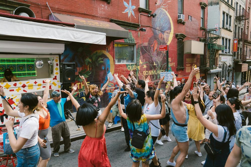 A large group of people dancing on the street in front of a mural