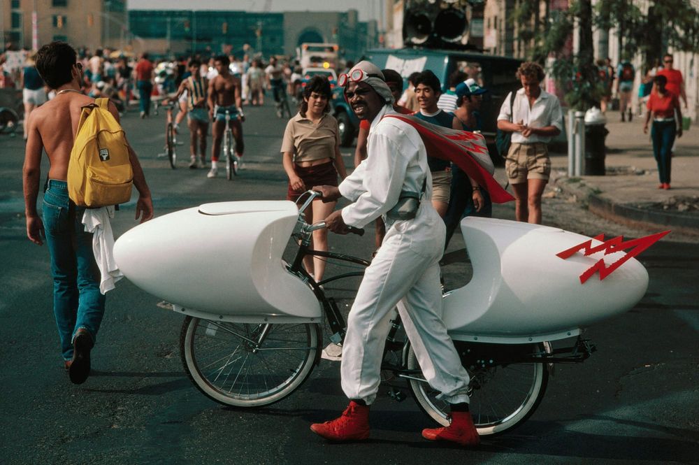 A man walks on Fifth Aveneue with a homemade speed bike.