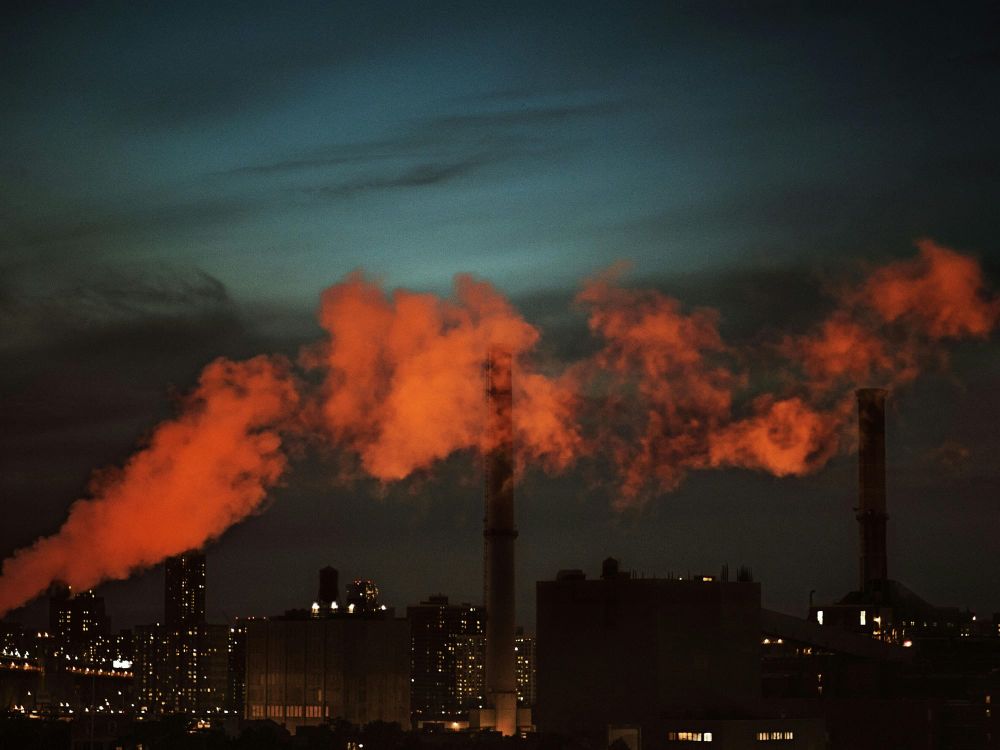 Orange smoke floats across the New York City skyline at dusk