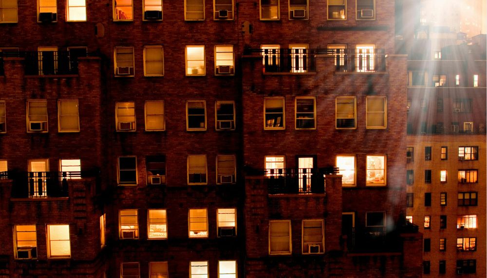 A view of an apartment building from the outside at night, with some windows lit up