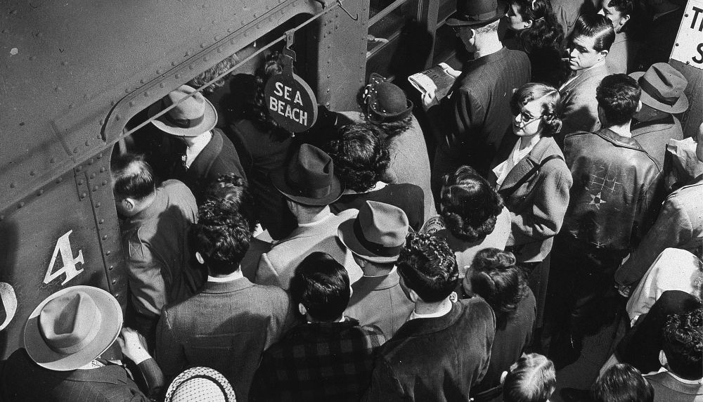 A black and white old photo of commuters entering a train