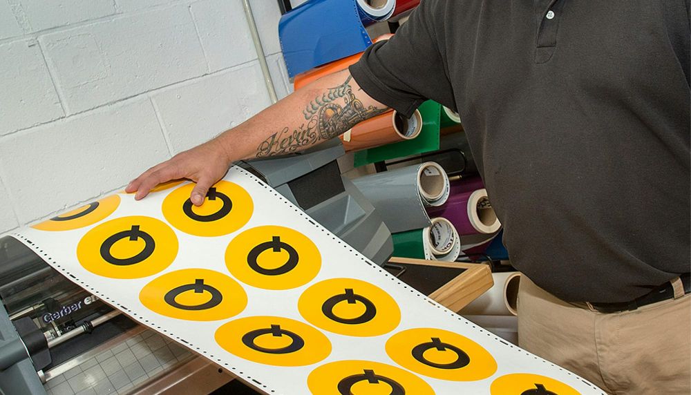 Man holds open a large printing page of the subway logo Q