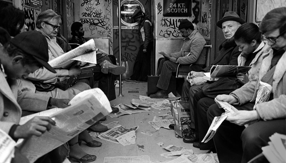 Vintage black and white photo of subway covered in graffiti and newspaper on the floor