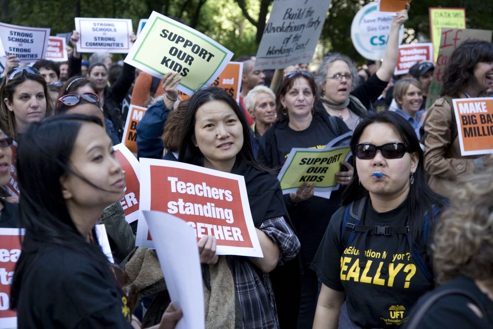 Members of the United Federation of Teachers hold signs at a rally