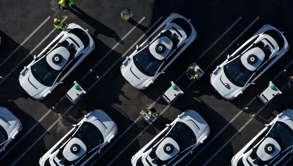 An overhead shot of two rows of Waymo robotaxis sitting parked in a lot