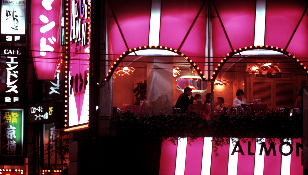 Night scene of Restaurant Almond at Roppongi Corner in Tokyo, lit in pink.