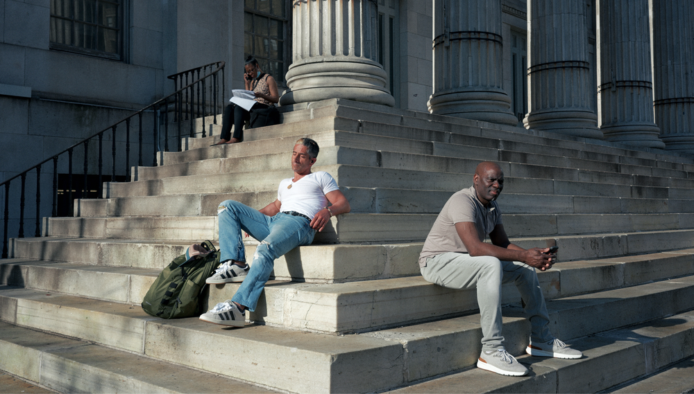 Three people sit on the steps outside of Brooklyn Borough Hall