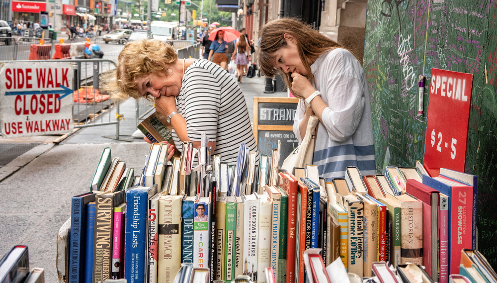Two women browse the bargain shelf outside The Strand booksto