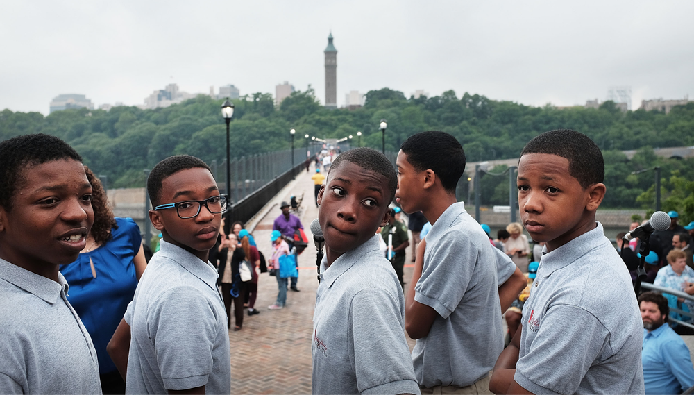 Five teenage boys who are members of the Highland Voices boys choir pause as pedestrians walk over the High Bridge, which connects Manhattan to the Bronx