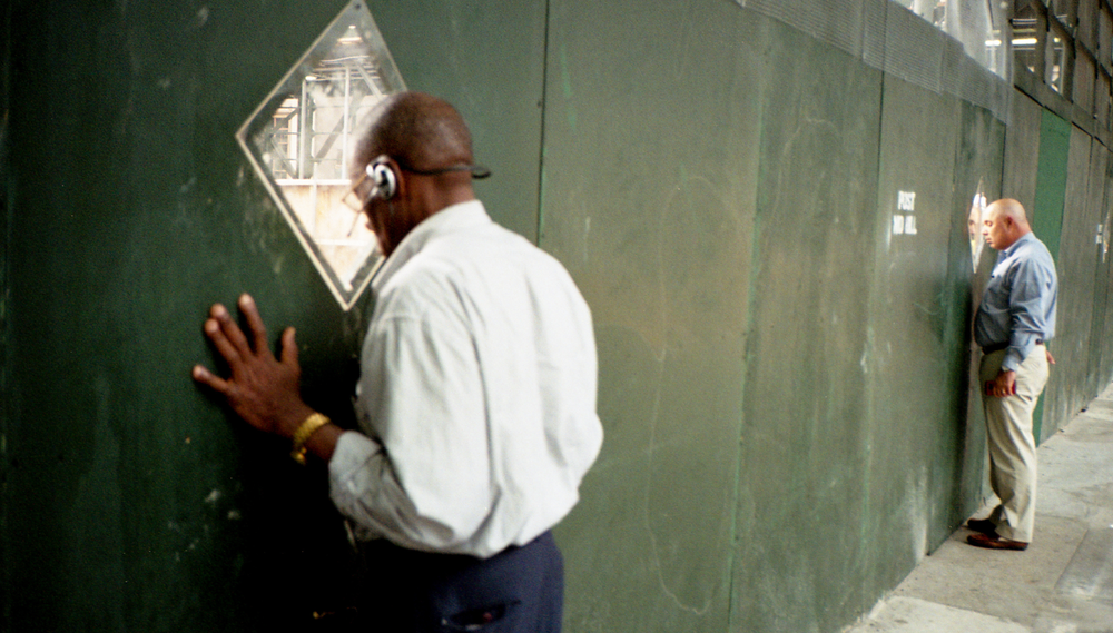 Two men in business clothes look through the windows of a construction site