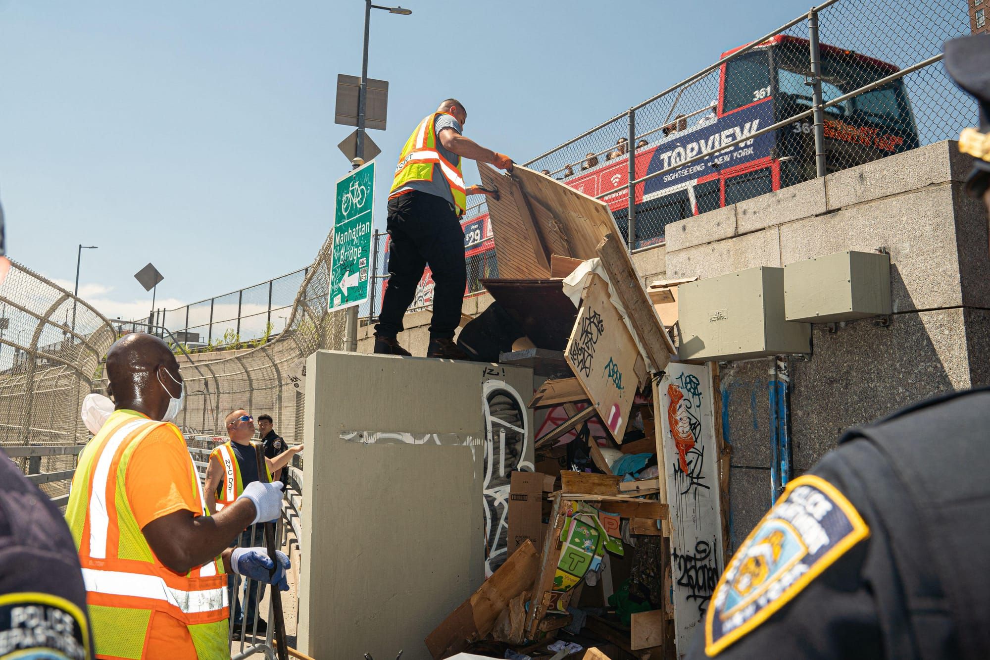 Sanitation workers and NYPD clear out a homeless encampment at the base of Manhattan Bridge