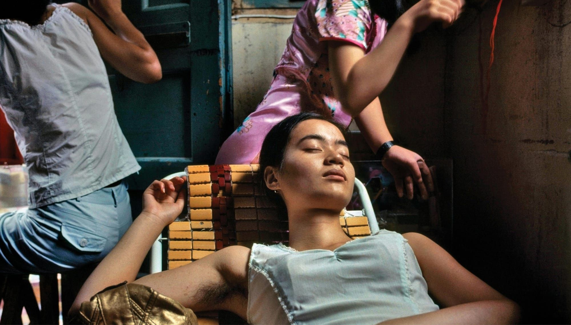 A woman lounges with her eyes closed on a lawn chair inside a restaurant with two other figures in the background