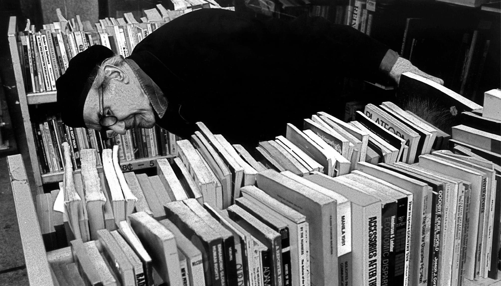 Elderly man leans down to look at library shelf