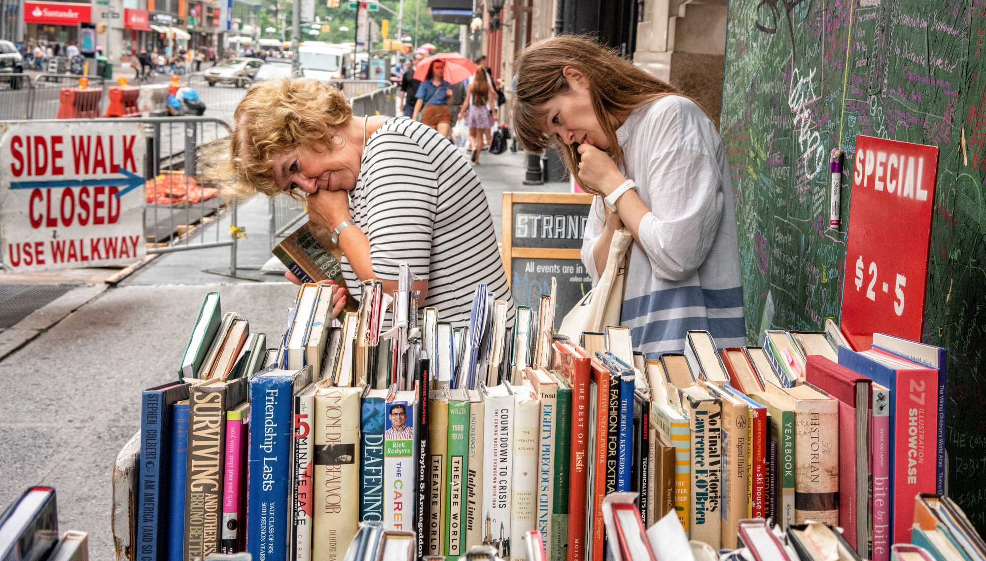 Two women browse the bargain shelf outside The Strand booksto