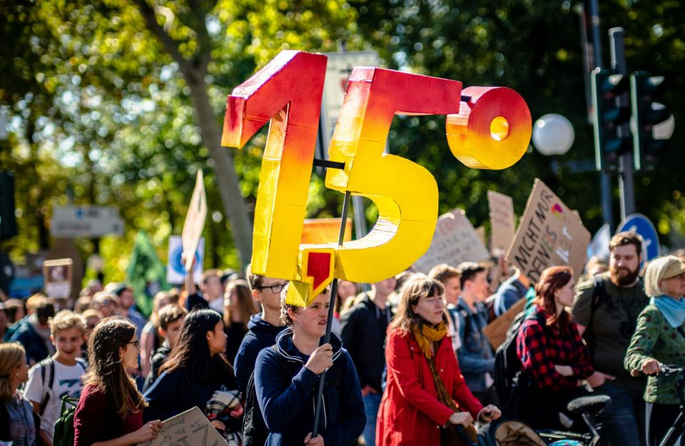 climate protestor holds up 1.5°C sign