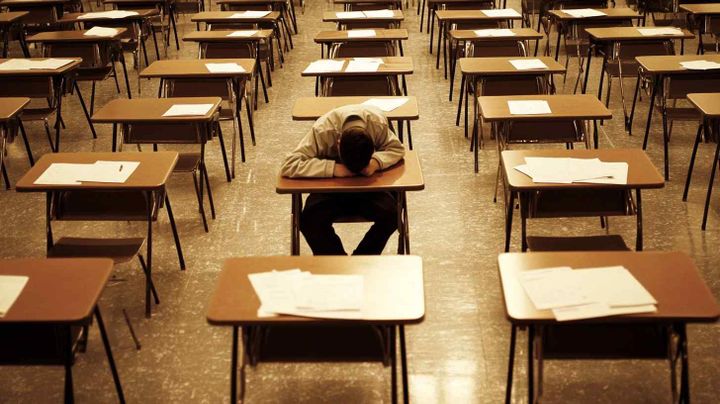 Image of a student in an exam room with his read on the desk