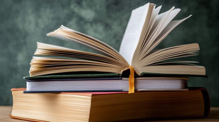 Image of a set of books on a table with the book on the top being half open