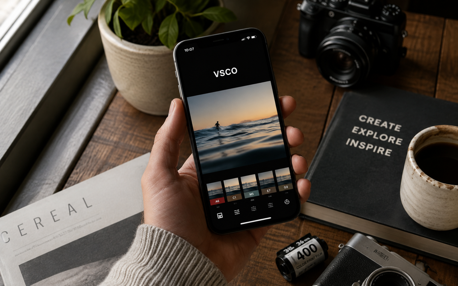 Overhead view of a smartphone editing a lifestyle photo in VSCO with photography accessories arranged on a warm editorial desk.