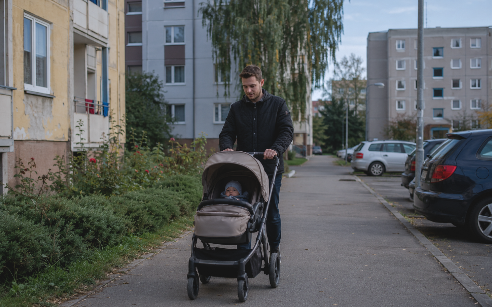 Father walking alone with his baby in a stroller through a residential neighbourhood.