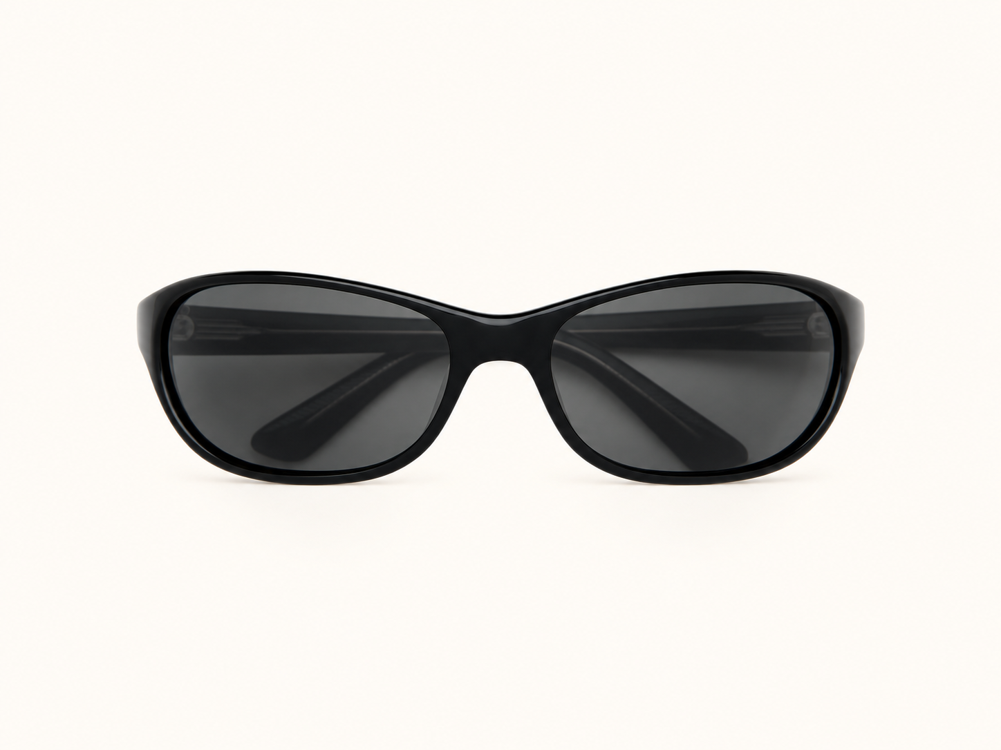 Black wraparound sunglasses with dark rectangular lenses, shown front-on against a warm ivory background.