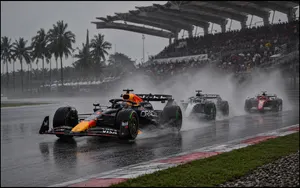 Three Formula 1 cars racing through heavy spray at Malaysia’s Sepang International Circuit.