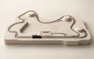 Minimalist Formula 1 circuit model in warm ivory stone with a black race car, pit lane and five red starting lights.