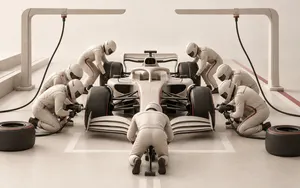 Formula 1 car surrounded by a full pit crew changing all four tyres in a clean cream-toned pit stop scene.