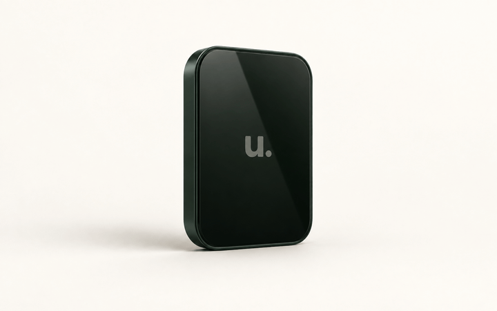 A dark green Unfinished app screen with the muted “u.” logo displayed on glossy black glass against a warm ivory background.