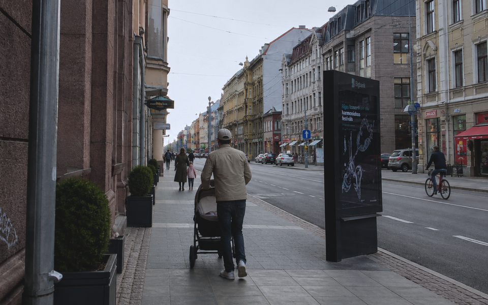 Father pushing a baby in a stroller along a street in central Riga.