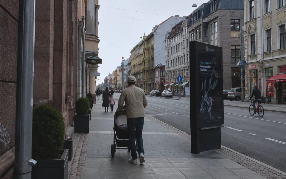Father pushing a baby in a stroller along a street in central Riga.