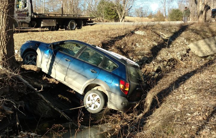 Car stuck in ravine with rescue flat bed truck.