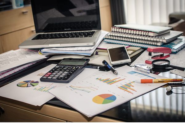 Desk with laptop, calculator, and charts, representing a quick SaaS audit and subscription review.