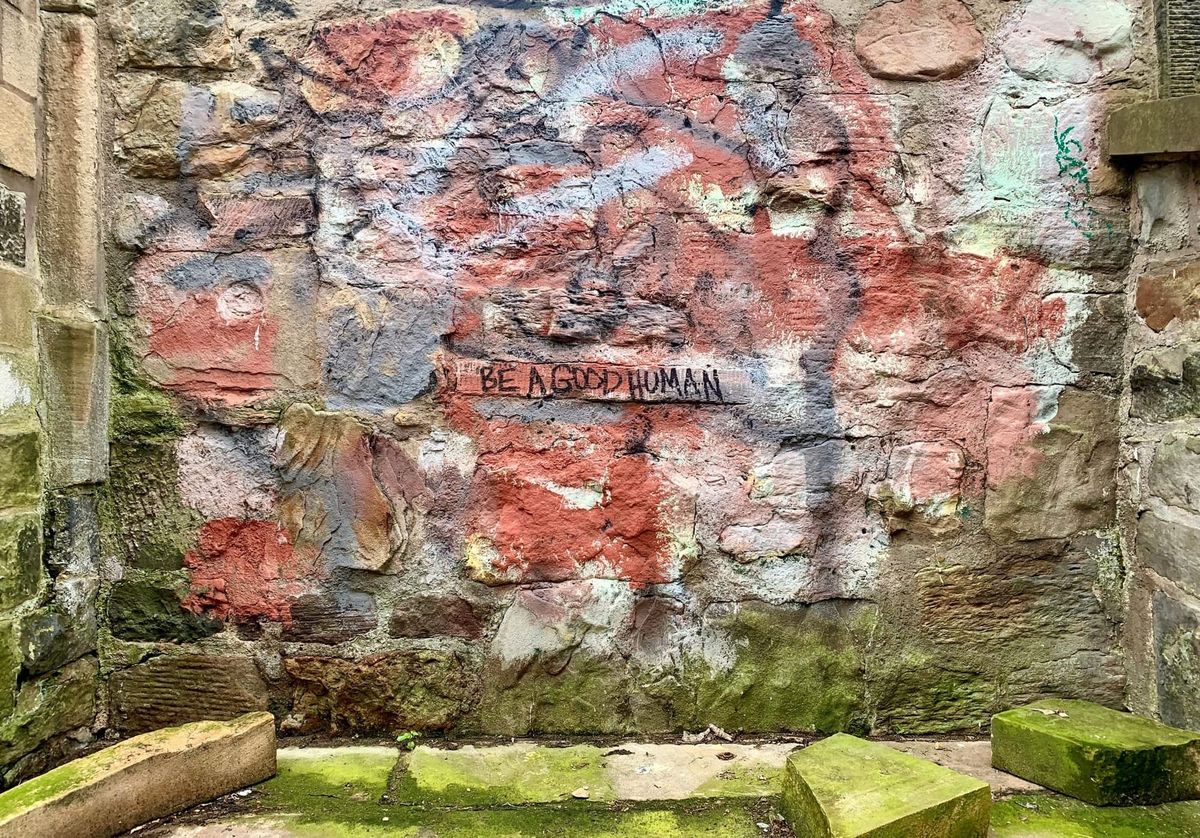 Old stone wall with grafitti text reading Be a good human. 