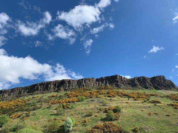 The Crags, Edinburgh, with a cloudy blue sky above. 