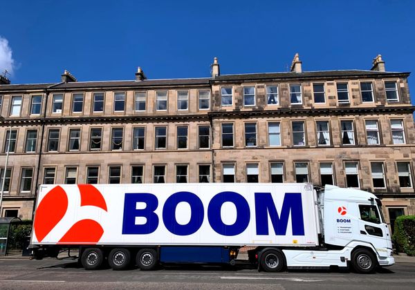 A white lorry with Boom branding with blue sky.
