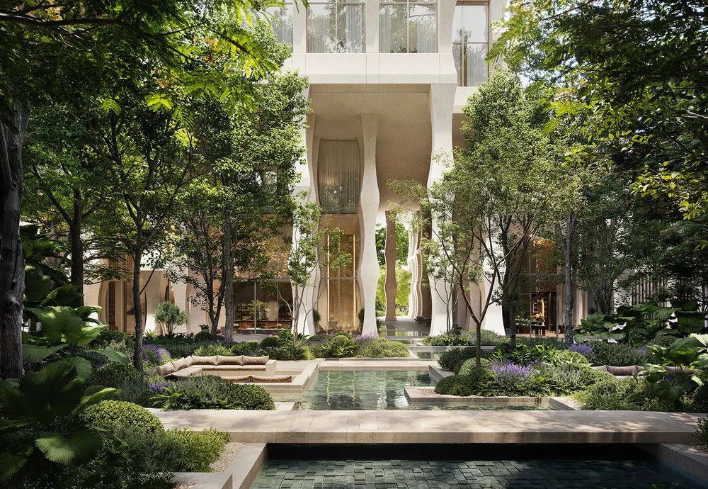 Lush courtyard garden with reflecting pools and a stone walkway, in front of a pale building with sculpted, curving columns