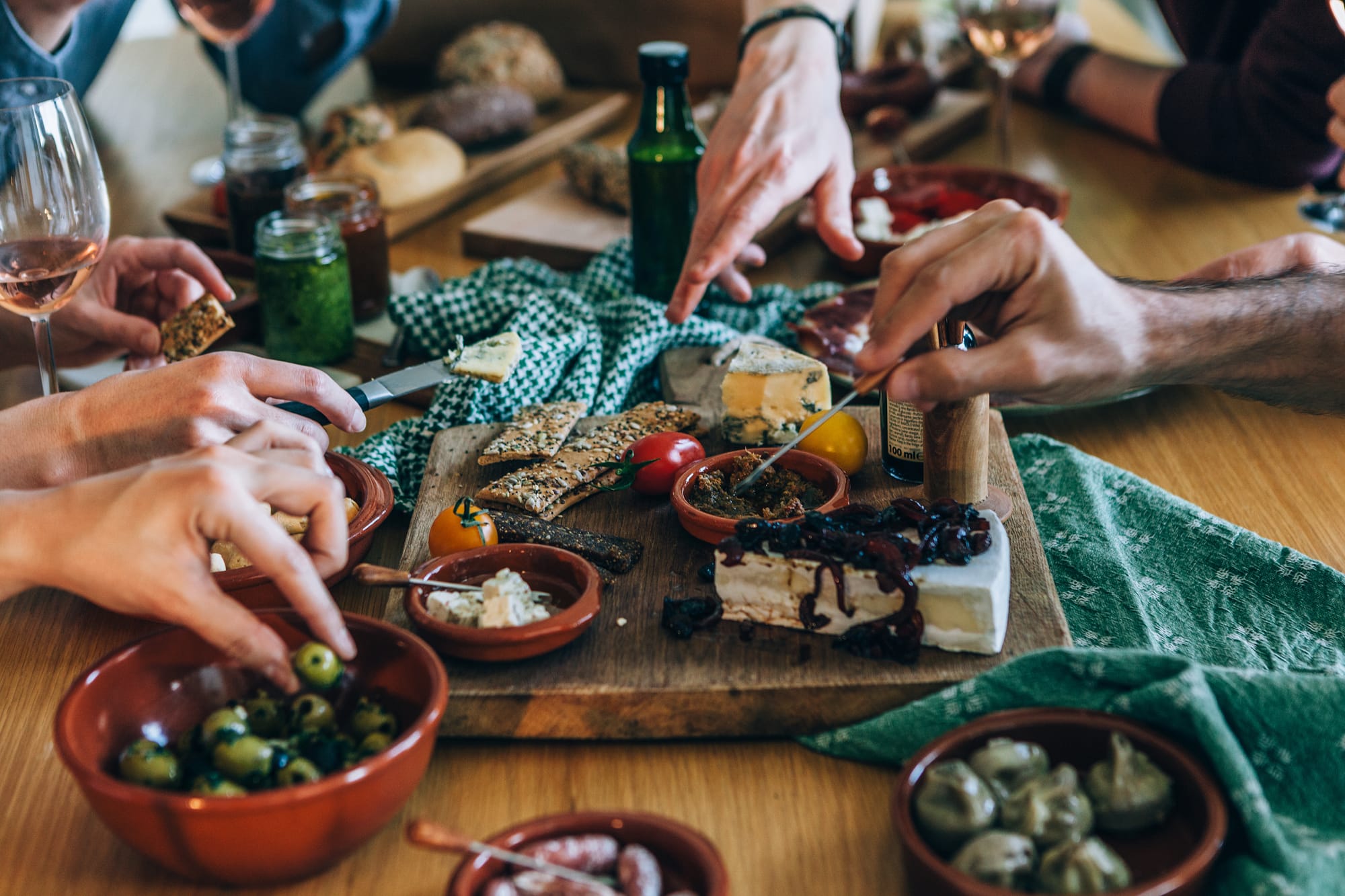 Multiple tapas on a table with wine glasses for each restaurant guest.