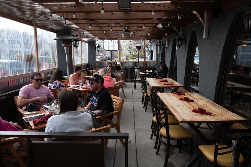 Restaurant patrons sit outside on a covered patio.
